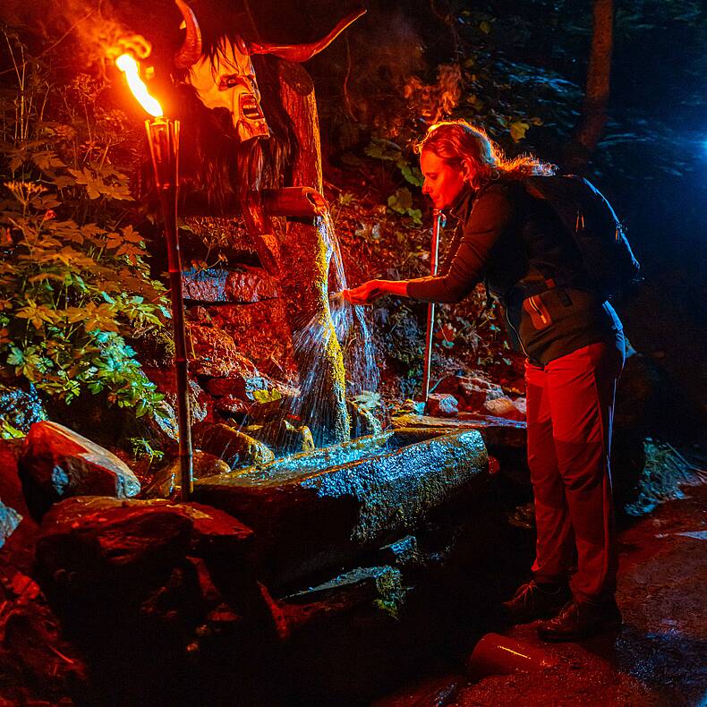 Mit Fackeln beleuchteter Brunnen mit frischem Quellwasser in der Groppensteinschlucht  